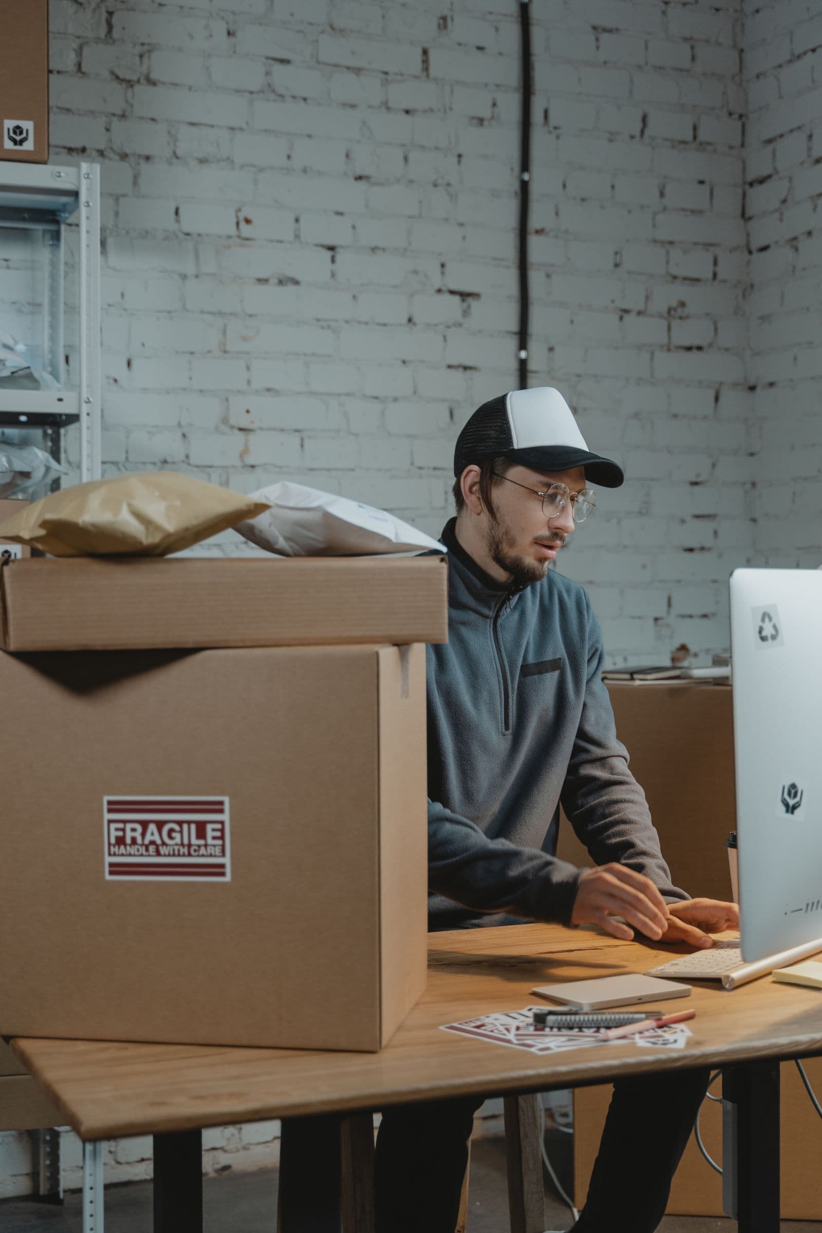 A warehouse worker managing shipments on a computer next to stacked parcels