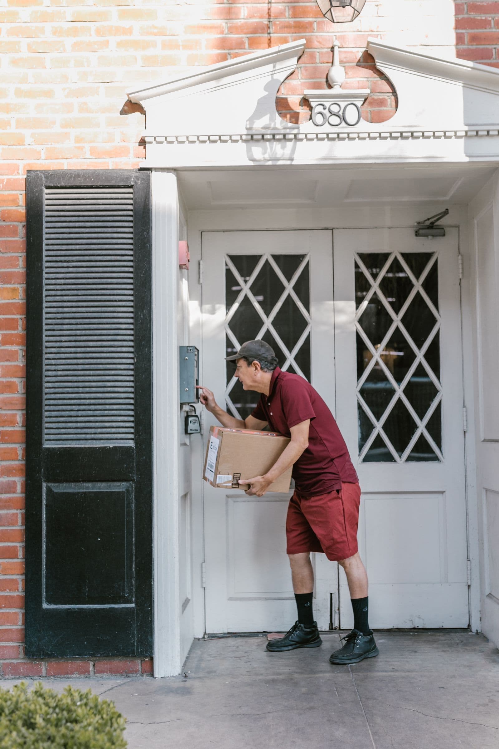 A uniformed courier smiling while handing a package to a customer at their door