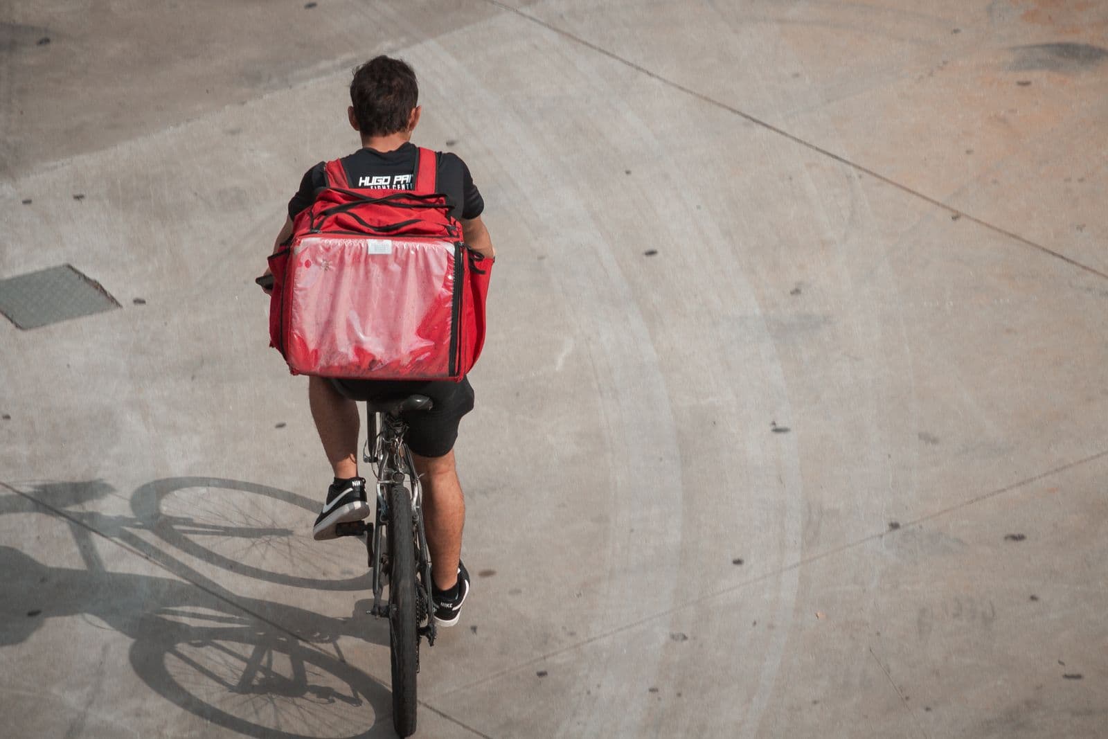 A delivery cyclist with an insulated backpack riding fast through the city